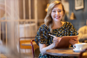 Female designer sketching with digital tablet and stylus at cafe Community Care Corps Supports Volunteer Caregivers